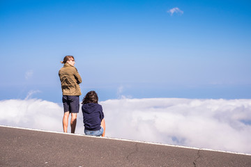 Couple enjoying  the  outdoor leisure activity looking at sea clouds at the mountain - young traveler in scenic destination