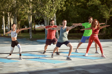 Group of young sporty people training together outdoors