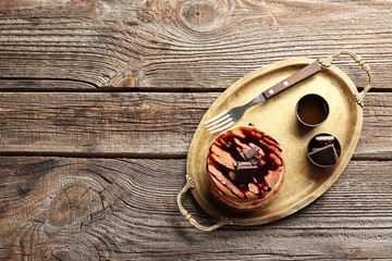Tray with tasty pancakes and chocolate on wooden table