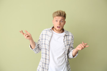 Shocked young man on color background