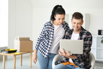 Happy couple with laptop planning design of their new house