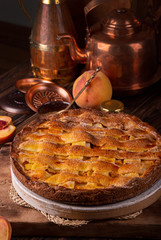 Homemade sweet pie cake with peach on white board on wooden rustic background