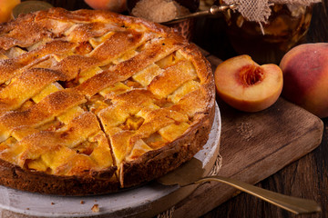 Homemade sweet pie cake with peach on white board on wooden rustic background
