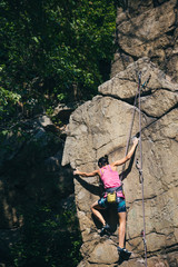 The girl climbs the granite rock.