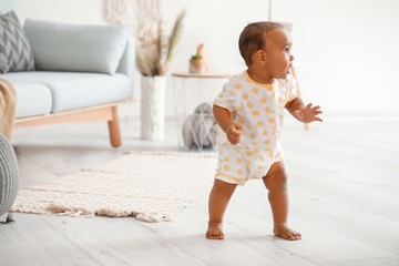 Cute little baby learning to walk at home