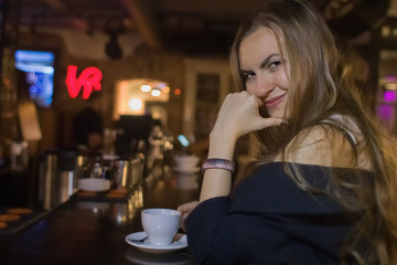 Young beautiful girl flirtatiously drinking coffee at the bar