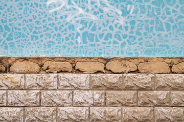Half wall with cracked blue paint and a half wall with tile wall