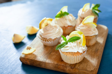 Obraz na płótnie Canvas Lemon cupcakes with poppy seeds, white butter cream and slice of lemon