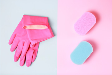 Rubber gloves and sponges on blue and pink background, top view, cleaning concept