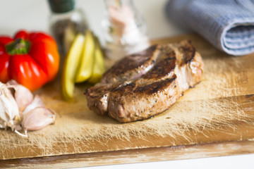 Grilled beef steak with vegetables on wooden cutting board