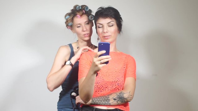 two lesbian girls dancing and looking at the smartphone screen
