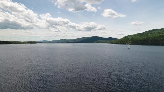 Aerial drone shot rising up above lake with sailboat