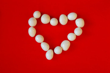 The contour of the heart of white stones on red (perspective, abstraction)