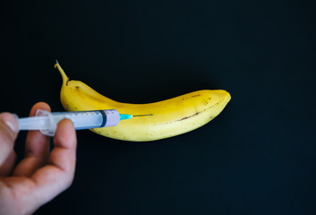 Man is putting injection in banana. GMP productos. Fruit with pesticide.