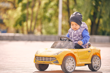 little boy riding a toy car in autumn park