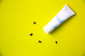 Insect repellent cream is lying in the table near dead flies.
