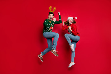 Full body photo of amazed jumping couple excited by x-mas prices wear ugly ornament jumpers and...