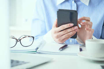 Close up of hand of businesswoman using smartphone at office. Business, technology and people concept.