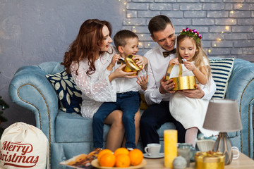 Happy Family Holding Christmas Gift Looking At Camera