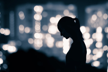 Sad silhouette of woman walking alone in the city at night. 