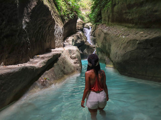 woman alone on the green canyon road at the middle of tropical jungle on the way of beautiful waterfall, Dao Falls in Cebu Island, Philippines