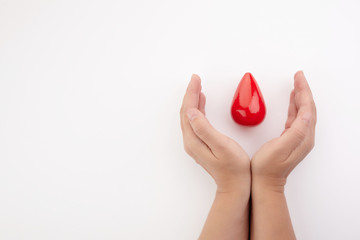 Two hands holding red blood drop on white background. Give blood. Donation concept.