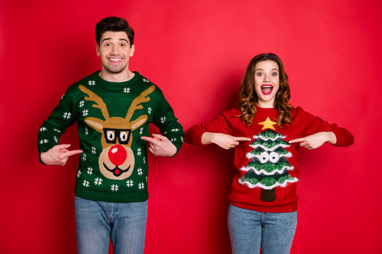 Midnight presents. Portrait of two brunet hair lovers people scream wow omg point indexf inger his her reindeer christmas tree pattern pullovers wear jeans isolated over red color background