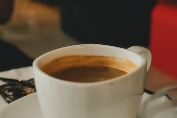 White hot cup of coffee in the cafe. Concept of aroma and relax.