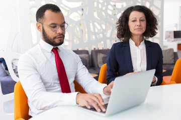 Obraz premium Businessman using computer during conference. Business man typing on laptop, his colleague looking at screen. Business conference concept