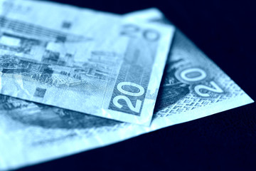 Two bills of twenty Hong Kong dollars on a dark background close-up. Blue color toned