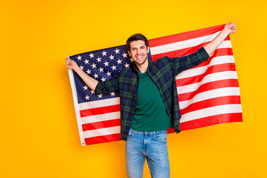 Photo of nice guy holding usa flag in hands excited to be exchange program student wear casual plaid shirt and jeans isolated yellow color background