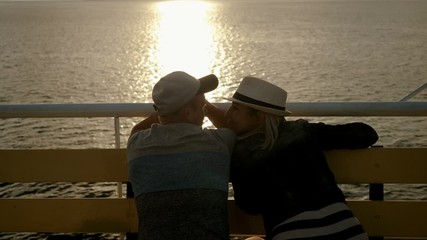A man and woman in love kissing and looking at sunset from the deck of a cruise ship sailing the Mediterranean sea. Greece. 4K