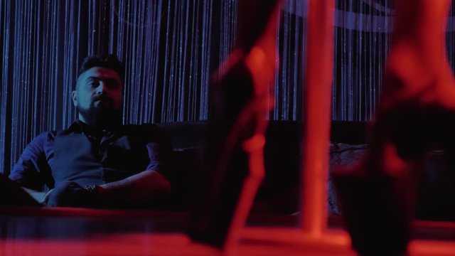 beautiful girl dances striptease on a pylon in a strip club for a client