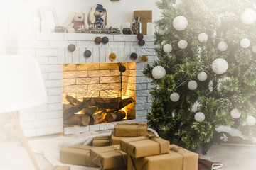 Decorated fir tree and gift boxes near fireplace in living room