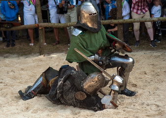 Knights in full armor are fighting in the arena. Medieval knight in the arena. Medieval knight in the Knight battles at the festival of medieval culture.