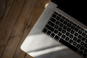 Laptop on table in the sun light. Keyboard button close-up. Freelancer workspace. Remote work in coworking or home. Design studio office. Modern mobile lifestyle. Online business, startup. Technology 