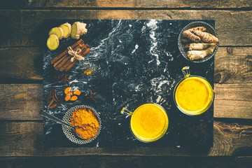 Turmeric golden milk and ingredients on wood background, copy space