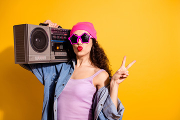 Photo of flirty lady with tape recorder on shoulder showing v-sign sending air kiss wear casual trendy clothes isolated yellow color background