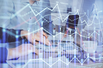 Multi exposure of chart with man typing on computer in office on background. Concept of hard work.