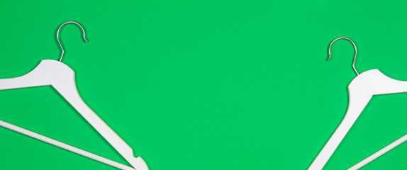 White wooden hangers on pastel green background. Shopping, sale, promo, social media, new season concept