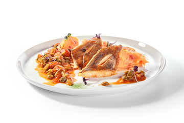 Pike perch or zander fillet with a side dish of tomatoes and capers served on a round platter