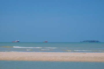  The sea has high waves, clear skies and a cargo ship.