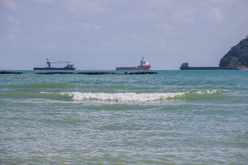  The sea has high waves, clear skies and a cargo ship.