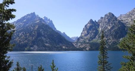Grand Teton Jenny Lake through forest pine tree mountains. Mountaineering, hiking, fishing and recreation.  2.5 million visitors a year. Geography, geology, environment, history, landscape.