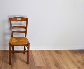 Single vintage wooden chair in front standing alone on wooden floor in empty room. Large copy space...