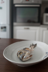 Fish bone left overs on a white oval plate.