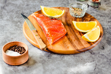 Slices of Salted smoked raw salmon with peppercorns and rosemary on a gray background.