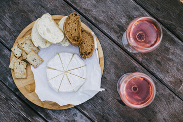 Camembert cheese, bread and crackers and two glasses of wine
