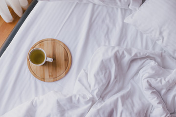 Cup of green tea in bed in cozy wooden house.