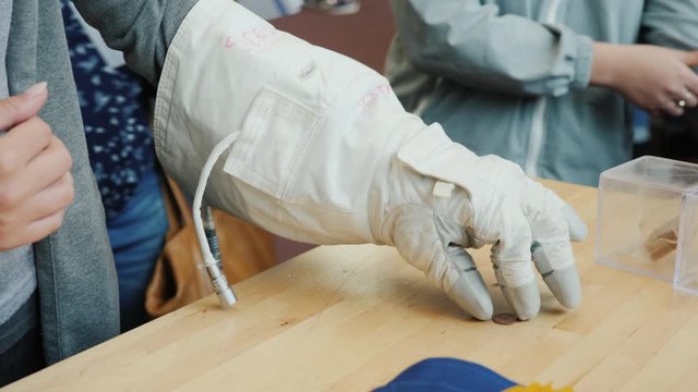 The man tries to make a coin in a space glove